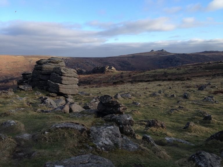 Moody Dartmoor scenic view of Saddle Tor in the distance from craggy Houndtor