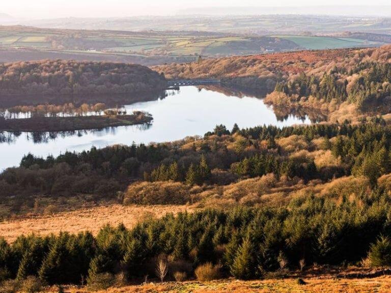 Scenic reservoir surrounded by woodlands full of autumnal colours