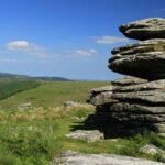 Striking Tor against beautiful backdrop of blue sky and lush green moorland