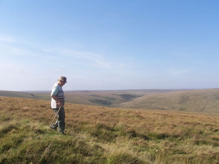 Man-soaked-in-sunshine-walking-across-open-moorland