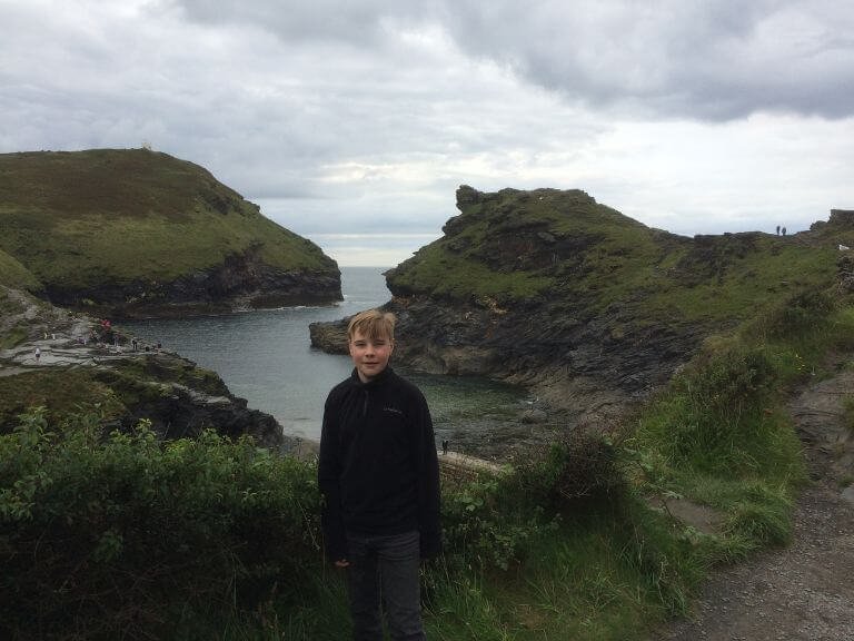 Young boy on coastal footpath with the 2 headlands of Boscastle in the background