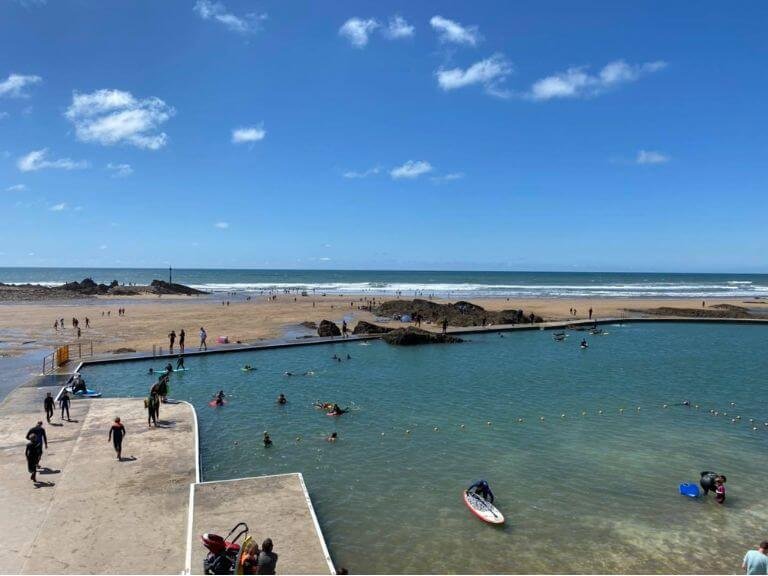 Trainee Surfers practising standing on boards in the safety and calm of Bude's Sea Pool by the beach