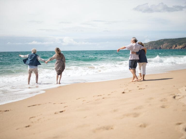 Two couples enjoying a walk along a sunny sandy Devon beach