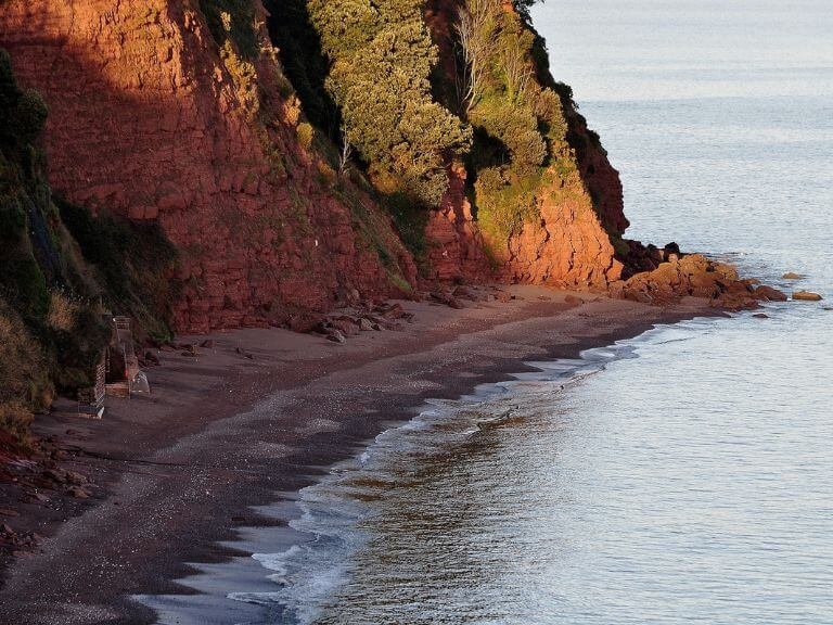 Quiet secluded cove at the foot of red cliffs in the twilight sun