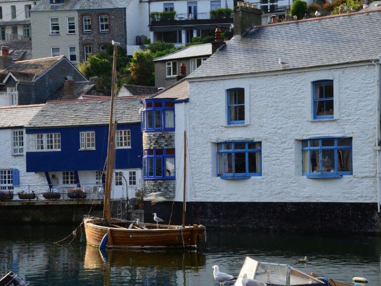 Fishing_boat-with_Seagull_in_front_of_picturesque_waterfront_cottages_in_Polperro