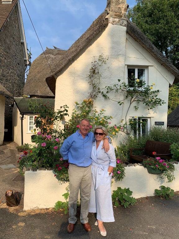 Owners in front of three pound cottage